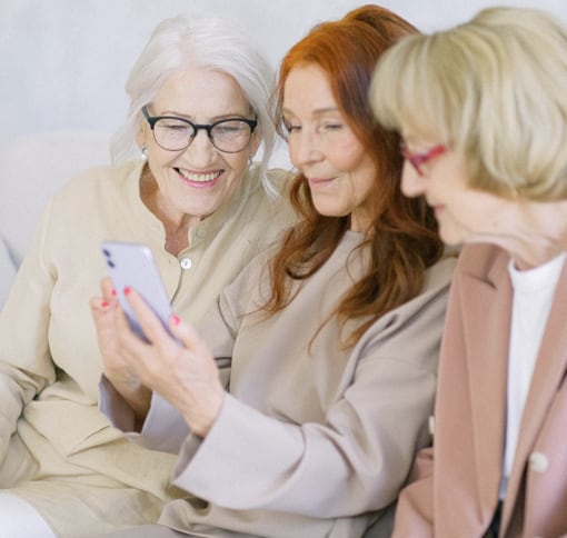 A group of three older women looking into a smartphone